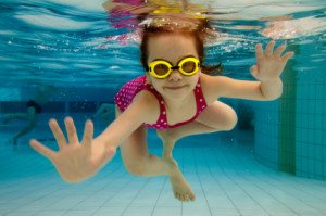 The girl smiles, swimming under water in the pool