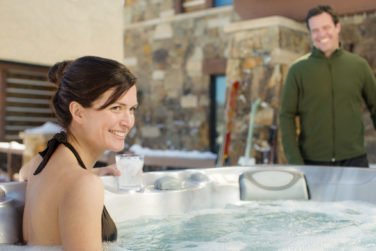Lady in hot tub and man in green coat in background