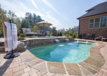 Fiberglass pool in backyard with tan umbrella