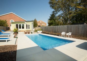 Rectangular pool with two white chairs in backyard - Dave Severance