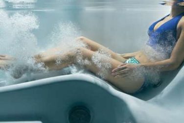 Benefits of hydrotherapy - girl underwater sitting in hot tub