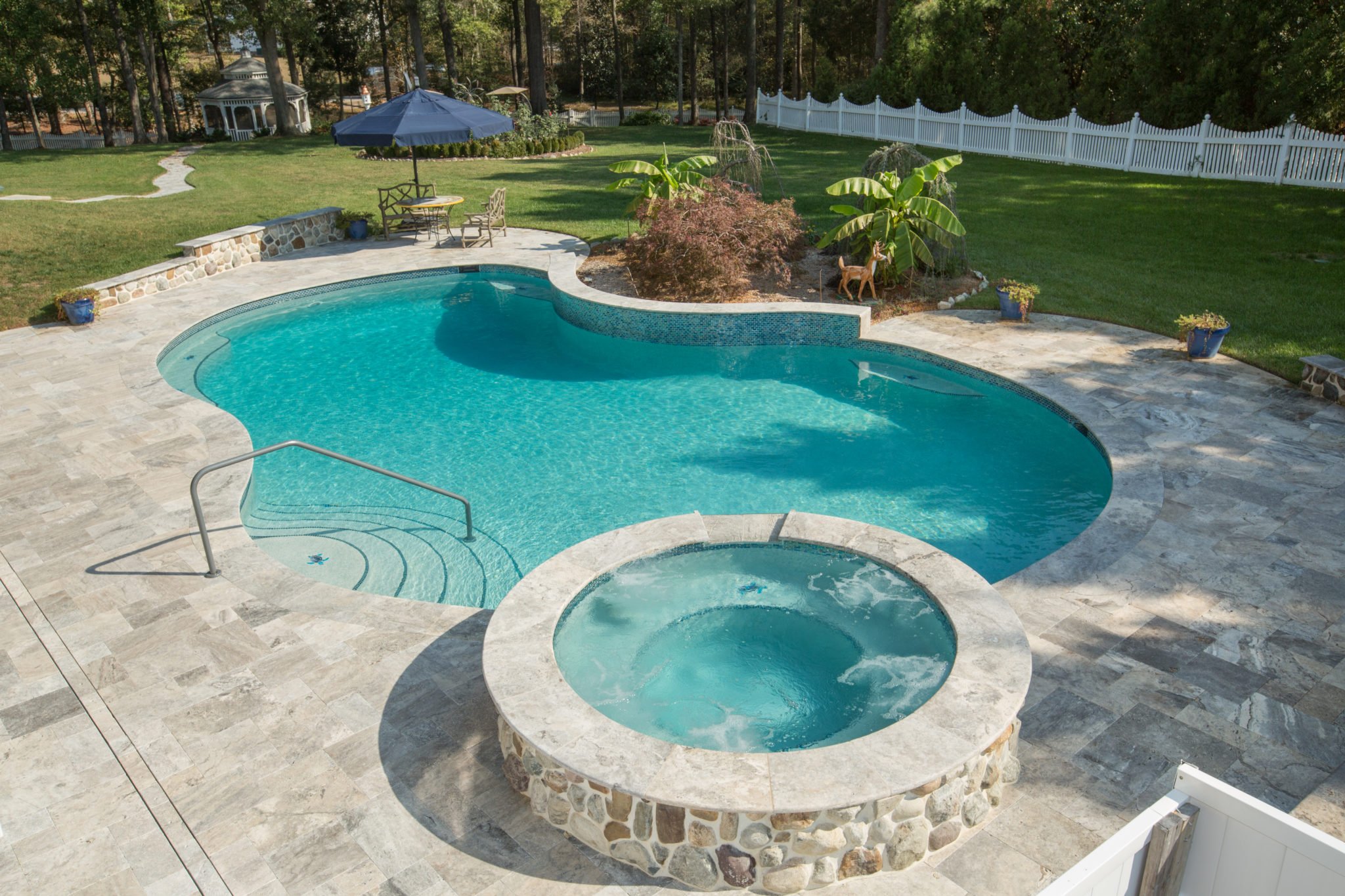 Pool and hot tub in backyard with dark blue umbrella