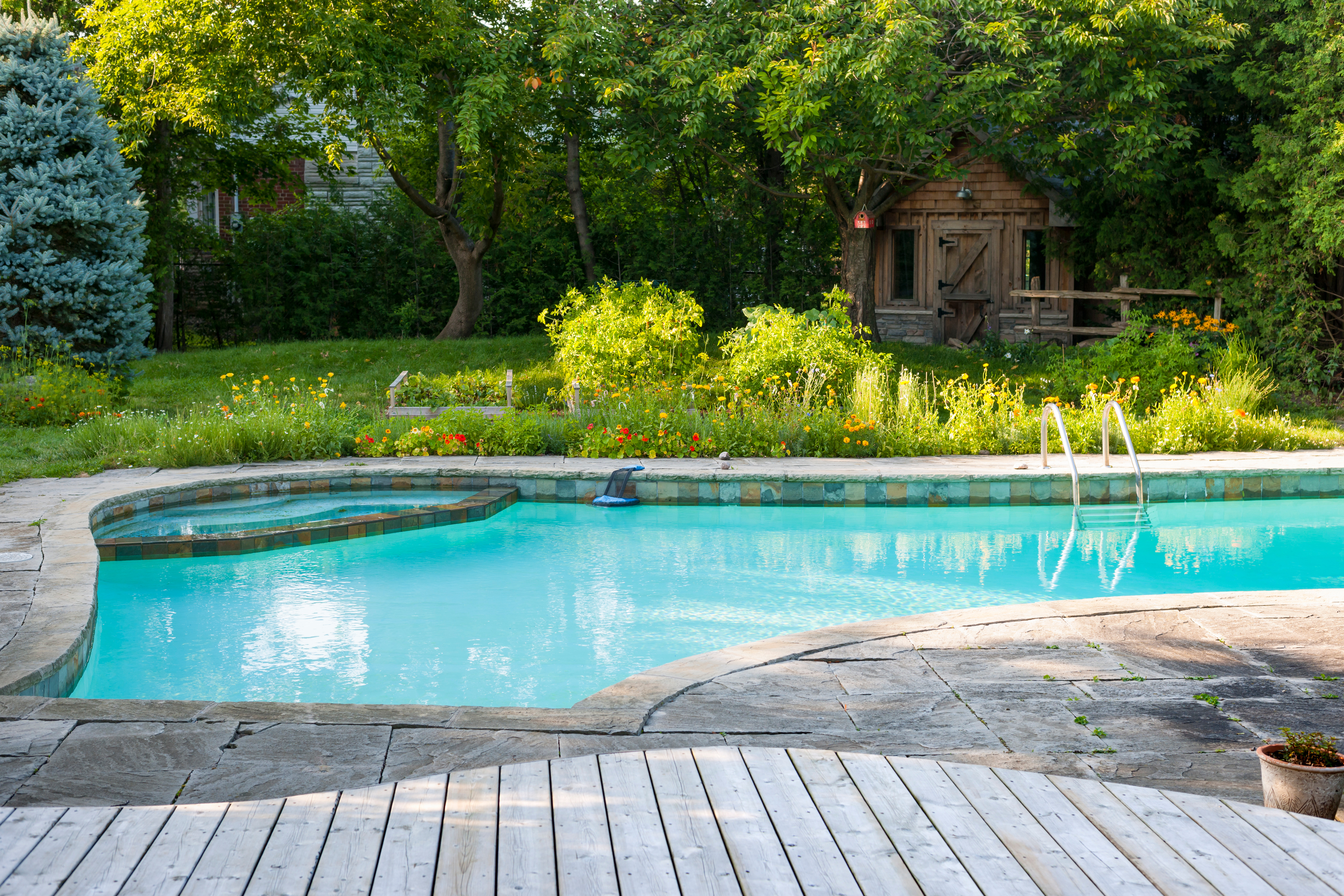 Concrete pool in backyard of home with gazebo.